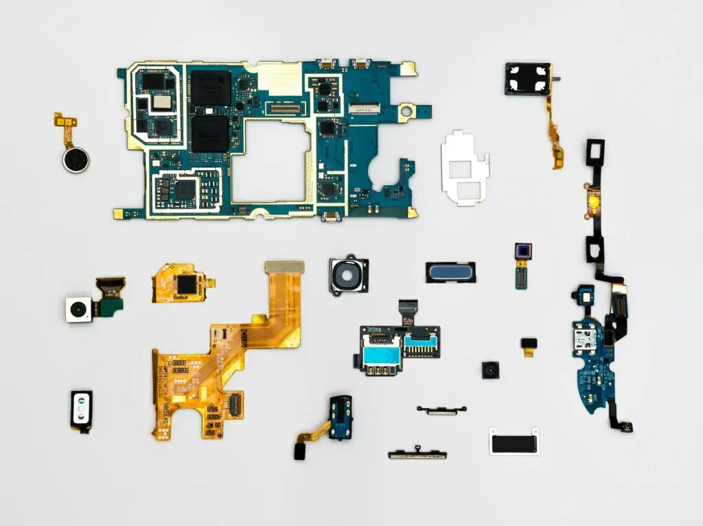 Eine Sammlung von elektronischen Komponenten, einschließlich Platinen, Kameramodulen und flexiblen Leiterplatten, sauber angeordnet auf einer weißen Oberfläche. Das Bild symbolisiert die Vielfalt und Modularität in der Elektronikentwicklung und betont die Bedeutung einer gut gepflegten Bauteilbibliothek.