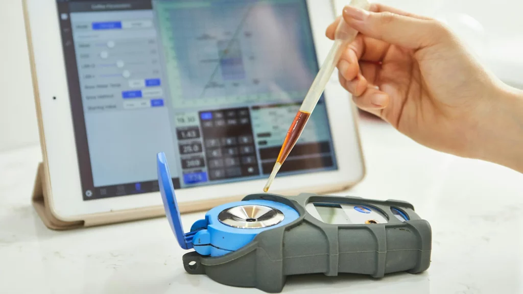 Hand pipettiert Flüssigkeit auf ein Messgerät, dass die Datn mithilfe von TinyML analysiert. Im Hintergrund ist ein Tablet mit Analyse-Software zu sehen.